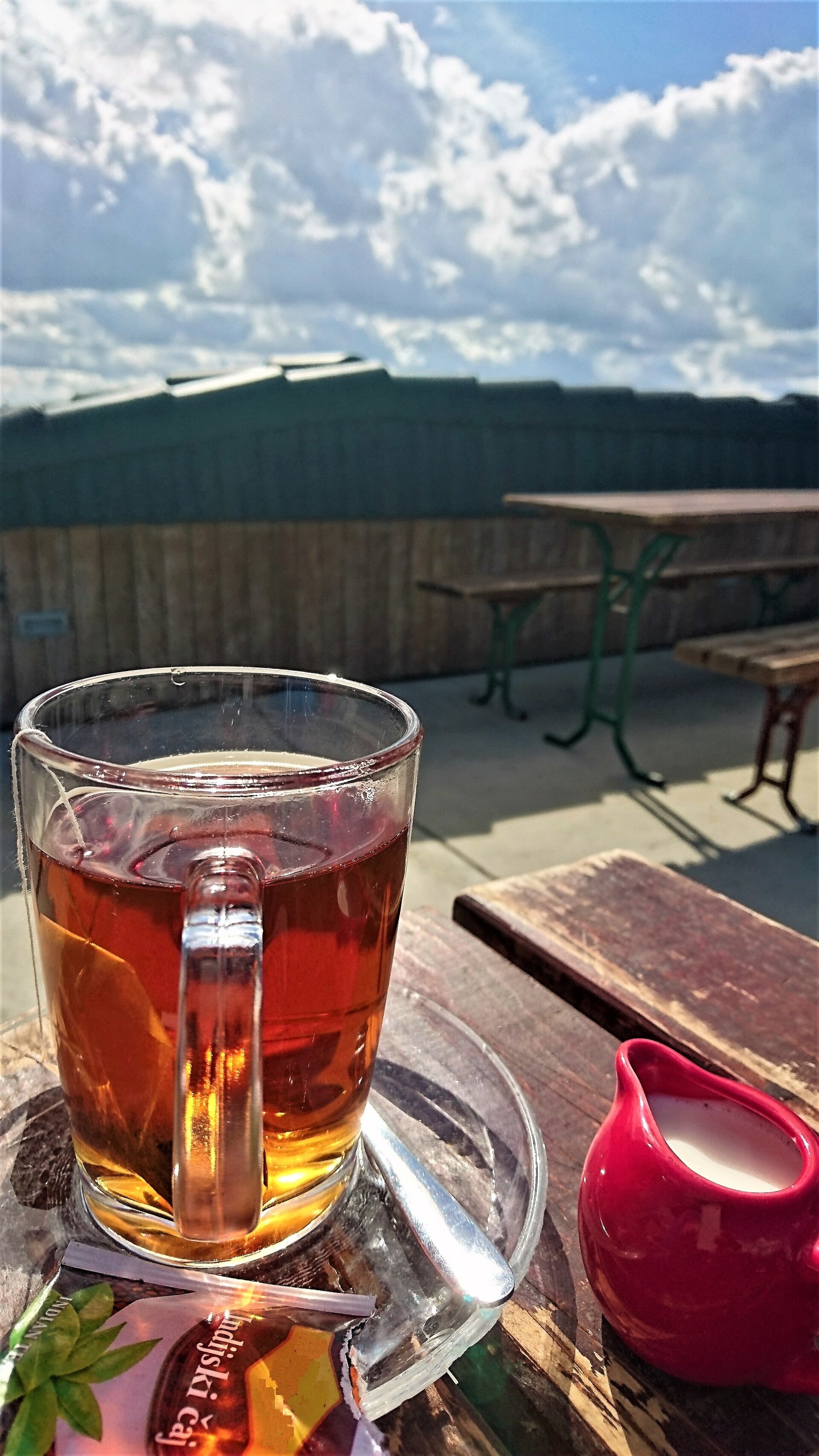 A cup of over-steeped dark tea beside a teabag
