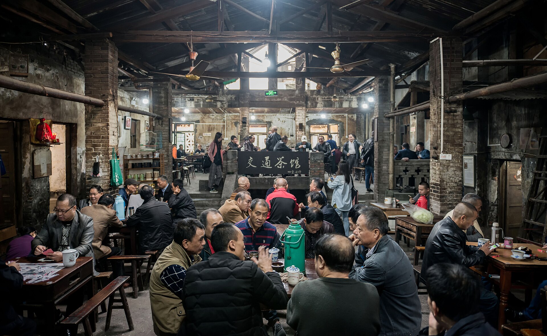 People chatting and drinking tea at wooden tables in a traditional Chinese teahouse