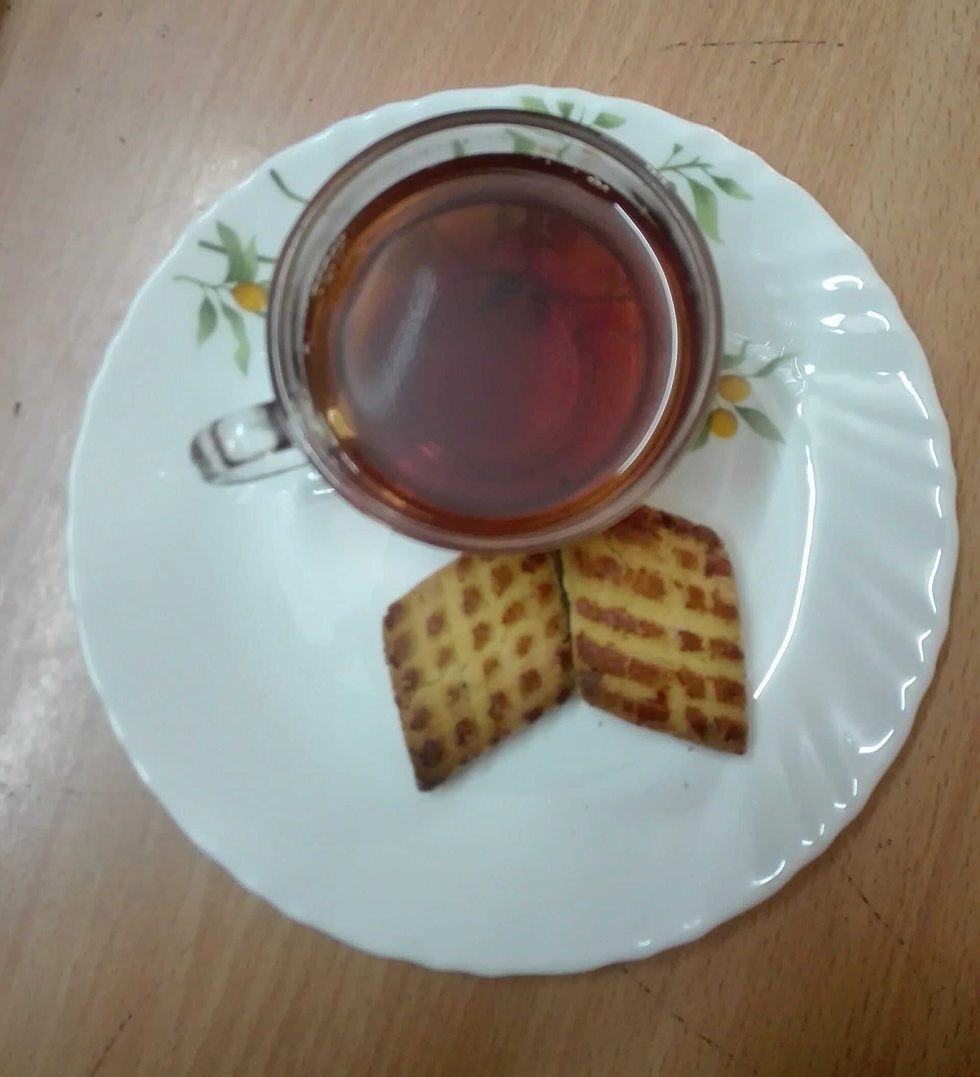 A cup of brewed tea with leaves beside it