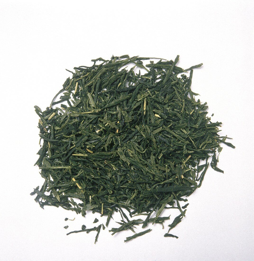 Steam rising from a kettle pouring water over green tea leaves