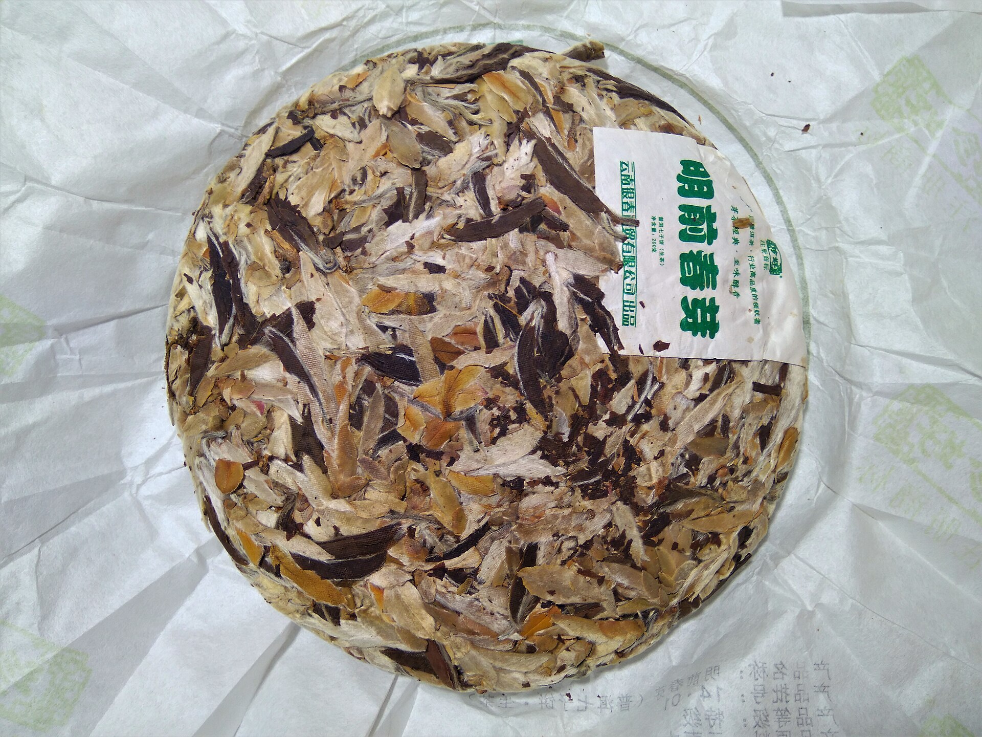 A compressed white pu-erh tea cake on its paper wrapper