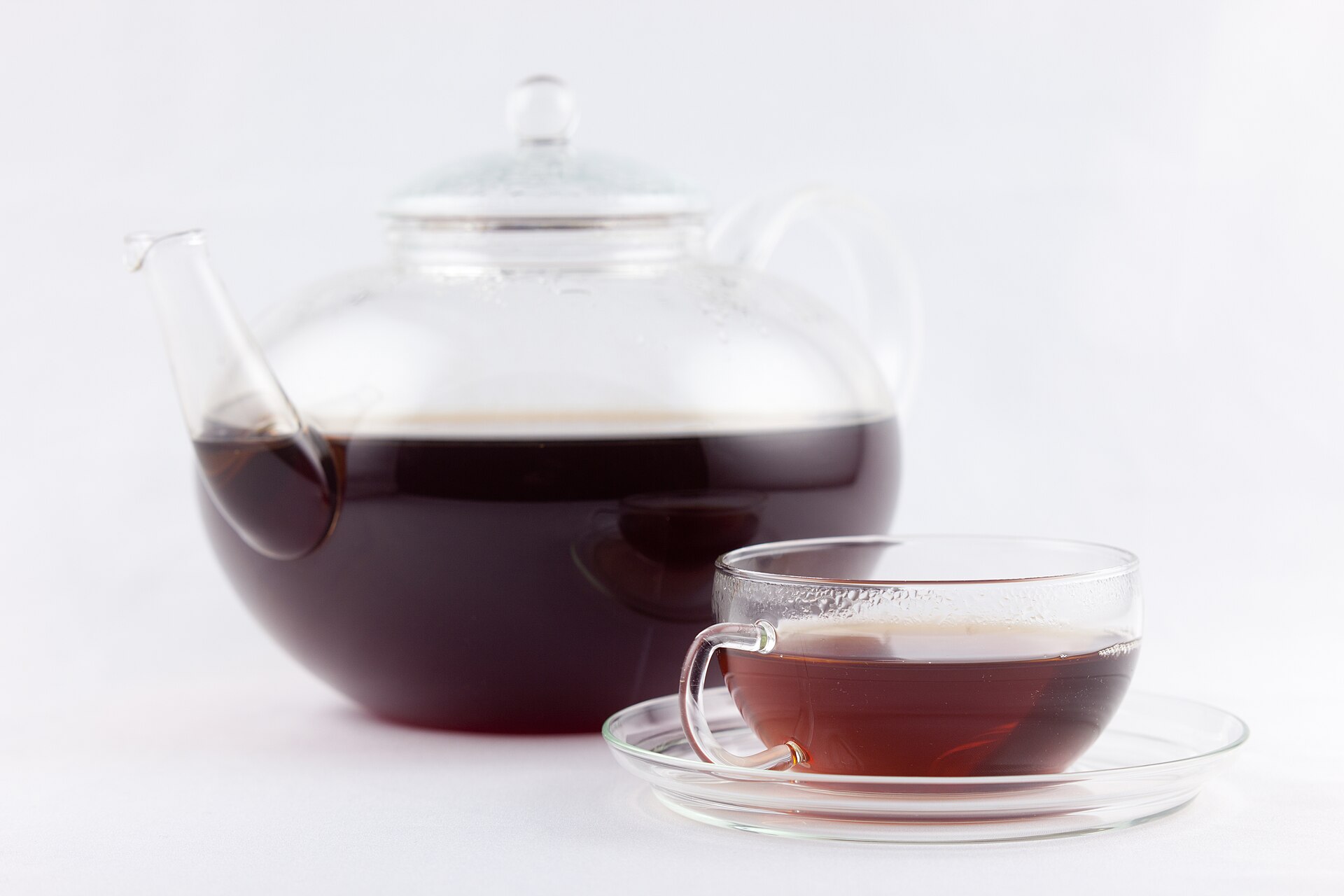 Tea leaves steeping in a glass teapot with a timer nearby